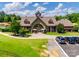 View of the neighborhood clubhouse, featuring manicured lawns, a circular driveway, and well-maintained parking at 18013 Grey Mossrun Dr, Charlotte, NC 28278