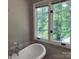 Bathroom featuring a freestanding bathtub, a large window, and marble tile accents at 2222 Raven Dr, Rock Hill, SC 29732