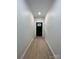 Neutral hallway featuring laminate flooring, white walls, and a black door at the end at 2412 Elizabeth Ave, Staley, NC 28150
