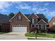 Charming two-story brick home with an attached two car garage, beautiful landscaping and a blue sky at 2563 Firethorn Ct, Gastonia, NC 28056