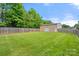 Large, expansive green backyard with a fence and a detached garage in the background, offering plenty of outdoor space at 2908 Dylan Nw Pl, Concord, NC 28027