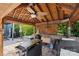 This outdoor kitchen features a ceiling fan, grill, ample counter space, and stone accents, creating an ideal space for entertaining at 2908 Dylan Nw Pl, Concord, NC 28027