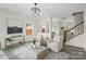 Bright living room with neutral tones, modern light fixture, and staircase access at 3092 Riker St, Clover, SC 29710