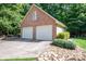 Two-car brick garage features white doors, situated in a serene, wooded setting with lush landscaping at 3513 Briarcliff Acres Dr, Lincolnton, NC 28092