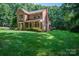 Two-story brick home with a manicured lawn, a front porch, and surrounded by lush greenery at 3513 Briarcliff Acres Dr, Lincolnton, NC 28092