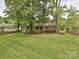 Large grassy backyard with mature trees providing ample shade, featuring a home with a porch and wooden fence at 4000 Chandworth Rd, Charlotte, NC 28210