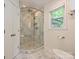 Bathroom with glass-enclosed shower featuring marble tile, a built-in shower seat, and a view to the backyard at 4000 Chandworth Rd, Charlotte, NC 28210