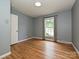 Empty bedroom with light blue walls, wood floors, a window, and white door at 4000 Chandworth Rd, Charlotte, NC 28210