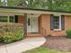 Close-up of a red brick home featuring a white front door and neatly trimmed landscaping at 4000 Chandworth Rd, Charlotte, NC 28210
