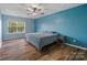 Comfortable bedroom with blue walls, a ceiling fan, and a large window providing lots of natural light at 4002 Paddle Wheel Ln, Indian Trail, NC 28079