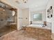 Bathroom with glass shower enclosure, soaking tub, tile floors, and natural light from window at 4290 Barbrick St, Sherrills Ford, NC 28673