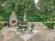Brick patio with an outdoor kitchen, fireplace, dining table and chairs with a wooded background at 4290 Barbrick St, Sherrills Ford, NC 28673