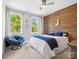 Stylish bedroom featuring a wood accent wall, complementary decor, and ample natural light from dual windows at 435 Galbreath Ct # 128, Fort Mill, SC 29708