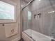 Modern bathroom features a ceramic tile shower-tub with glass doors and a window for natural lighting at 574 Crescent Rd, Rockwell, NC 28138