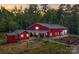 Beautiful red barn-style home with covered patio and professional landscaping at sunset at 574 Crescent Rd, Rockwell, NC 28138
