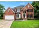 Traditional red brick home with black shutters, arched windows, attached garage, and lush green lawn at 6432 Morningsong Ln, Charlotte, NC 28269