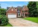 Traditional brick home featuring an attached garage and professionally landscaped lawn at 6432 Morningsong Ln, Charlotte, NC 28269