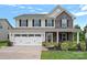 Charming two-story home featuring stone accents, a manicured lawn, and an attached two-car garage at 7331 Millstone Sw Cir, Concord, NC 28025