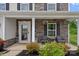 Inviting front porch with stone accents, a seating area, and beautifully landscaped garden beds at 7331 Millstone Sw Cir, Concord, NC 28025