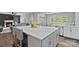 Bright kitchen featuring an island with marble countertop, gray cabinetry, and stainless steel appliances at 7331 Millstone Sw Cir, Concord, NC 28025