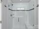 Shower featuring glass doors, tiled walls, and built-in shelving for toiletries at 7331 Millstone Sw Cir, Concord, NC 28025