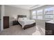 Bright bedroom featuring neutral walls, large window, and a comfortable queen-sized bed and carpet at 8928 Morning Mist Rd, Charlotte, NC 28215