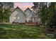 A lovely backyard with a deck, chairs, a fire pit and a well-maintained lawn at dusk creates a serene outdoor space at 134 Lake Spring Loop, Mooresville, NC 28117