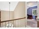 Open hallway with stairway chandelier that leads to carpeted secondary bedroom at 134 Lake Spring Loop, Mooresville, NC 28117