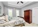 Bedroom featuring tray ceiling, fan, two windows, and a stylish bed with decorative pillows and linens at 7023 Blakeney Greens Blvd, Charlotte, NC 28277