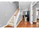 Inviting foyer featuring hardwood floors, staircase, neutral paint, and open access to other rooms at 7023 Blakeney Greens Blvd, Charlotte, NC 28277