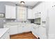 Bright kitchen features white appliances and cabinets, and beautiful hardwood floors at 7023 Blakeney Greens Blvd, Charlotte, NC 28277