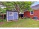 Charming backyard featuring a blue shed, well-manicured lawn, and garden area, creating a serene outdoor space at 10024 Tealridge Ln, Charlotte, NC 28277