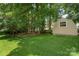 Large backyard with green grass, mature trees, and a small storage building at 1012 Lightwood Dr, Matthews, NC 28105