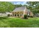 Beautifully landscaped front yard featuring green grass, mature trees, and charming front porch at 1012 Lightwood Dr, Matthews, NC 28105