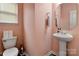 Half bathroom with toilet, pedestal sink, light pink walls, and wood-look floors at 1017 Quail Run Ct, Indian Land, SC 29707