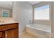 Bright bathroom featuring a soaking tub and single sink vanity with dark wood cabinets at 1017 Quail Run Ct, Indian Land, SC 29707