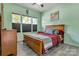 Cozy bedroom with neutral green walls, a wood-framed bed, three windows and stylish window blinds at 1017 Quail Run Ct, Indian Land, SC 29707