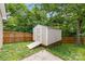 Backyard view of the wooden storage shed with ramp, nestled among green trees and grassy area at 104 E Louisiana Ave, Bessemer City, NC 28016