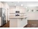 Lovely kitchen features white cabinets, stainless steel appliances, and a granite island open to living room at 14611 Murfield Ct, Charlotte, NC 28278