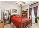 Comfortable bedroom featuring a four-poster bed with red quilt, a window with brown curtains, and a ceiling fan at 163 Carmen Way, Lancaster, SC 29720