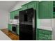 Bright kitchen with stainless steel appliances, hardwood floors, subway tile backsplash, and ample green cabinetry at 213 Genesis Pl, Cleveland, NC 27013