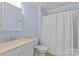 Bathroom with a vanity sink, toilet, and tub with a white shower curtain at 2814 Glendale Rd, Charlotte, NC 28209