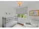 Bright Bedroom features a metal crib, stylish chandelier, and a comfortable armchair near a window at 2814 Glendale Rd, Charlotte, NC 28209