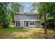 Backyard view with lush lawn and back of house, showing a small patio and mature trees at 3826 Yorkford Dr, Charlotte, NC 28269