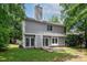 View of backyard and house, showing back patio, siding, chimney and mature trees at 3826 Yorkford Dr, Charlotte, NC 28269
