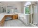 Bright bathroom boasts tile floors, tub under window, wood cabinets and walk-in shower with gold frame at 3826 Yorkford Dr, Charlotte, NC 28269