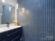 Chic powder room featuring a blue herringbone tile wall, modern vanity and a decorative mirror at 4049 Shadowbrook Rd, Waxhaw, NC 28173