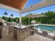 Elegant outdoor kitchen featuring a built-in grill, pizza oven, and bar seating near the refreshing pool at 4049 Shadowbrook Rd, Waxhaw, NC 28173