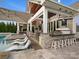 Luxurious outdoor kitchen with a built-in grill, pizza oven, bar seating, and poolside lounge chairs at 4049 Shadowbrook Rd, Waxhaw, NC 28173