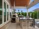 Stylish outdoor kitchen with a pizza oven, built-in grill, bar seating, and a view of the lush backyard at 4049 Shadowbrook Rd, Waxhaw, NC 28173